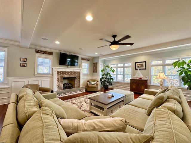 living room with crown molding, ceiling fan, hardwood / wood-style floors, a fireplace, and beamed ceiling