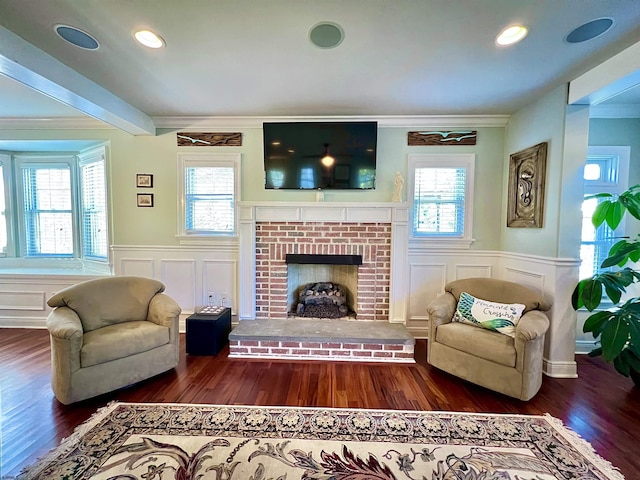 living room featuring crown molding, plenty of natural light, dark hardwood / wood-style floors, and a fireplace