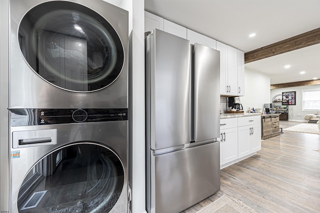 laundry area featuring stacked washer / dryer and light hardwood / wood-style flooring