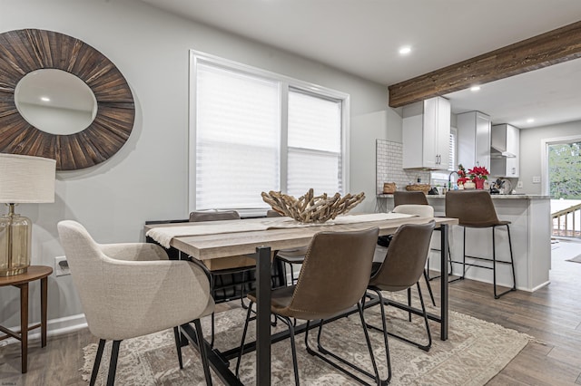 dining space featuring wood-type flooring and beam ceiling