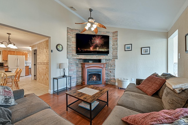 living room with crown molding, ceiling fan, lofted ceiling, and light wood-type flooring