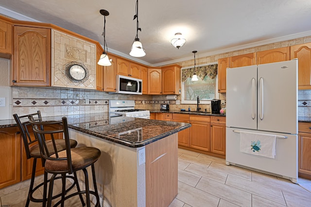 kitchen featuring sink, a center island, dark stone countertops, pendant lighting, and white appliances