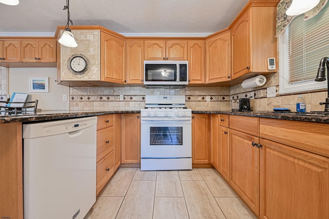 kitchen with tasteful backsplash, dark stone countertops, white appliances, and decorative light fixtures