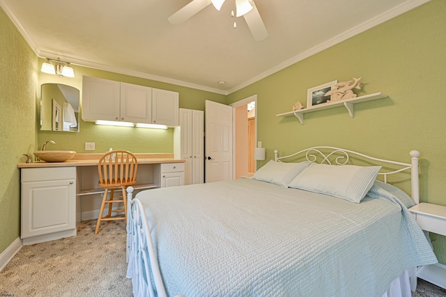 carpeted bedroom with sink, crown molding, built in desk, and ceiling fan