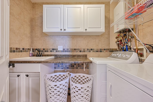 clothes washing area featuring cabinets, sink, tile walls, and washing machine and clothes dryer