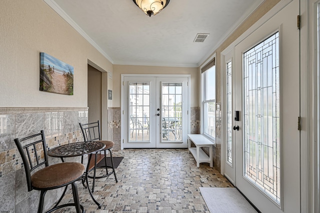 entryway featuring french doors, crown molding, and tile walls