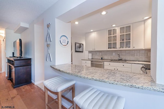 kitchen featuring a breakfast bar, dishwasher, kitchen peninsula, and white cabinets