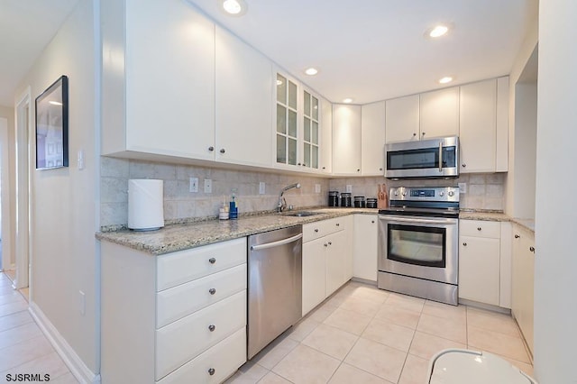 kitchen featuring appliances with stainless steel finishes, white cabinetry, sink, backsplash, and light tile patterned floors