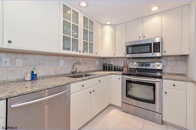 kitchen with sink, light tile patterned floors, stainless steel appliances, and white cabinets