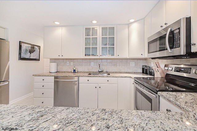 kitchen with sink, appliances with stainless steel finishes, backsplash, light stone countertops, and white cabinets