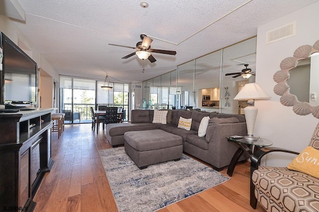 living room featuring hardwood / wood-style flooring, ceiling fan, lofted ceiling, and a textured ceiling