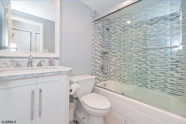 full bathroom with toilet, vanity, and shower / bath combination with glass door