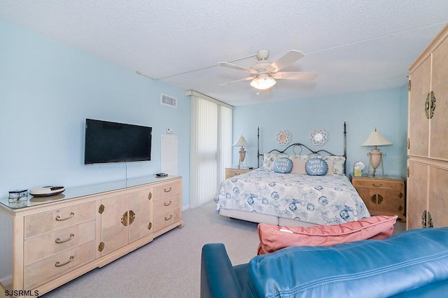 bedroom featuring light carpet, a textured ceiling, and ceiling fan