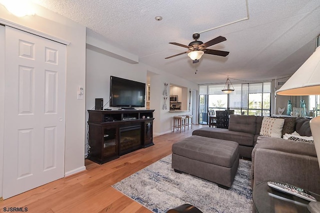 living room featuring ceiling fan, hardwood / wood-style flooring, and a textured ceiling