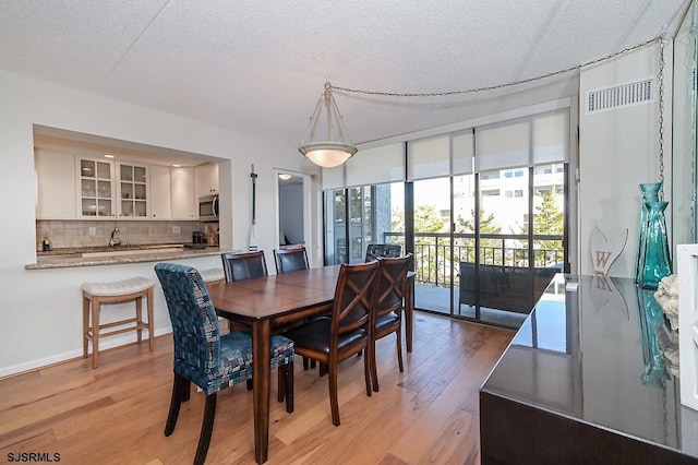 dining room with light hardwood / wood-style flooring and a textured ceiling