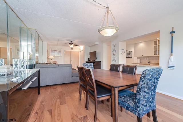 dining room with ceiling fan, light hardwood / wood-style flooring, and a textured ceiling