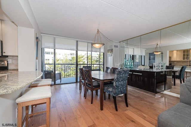 dining space featuring floor to ceiling windows, light hardwood / wood-style flooring, and a textured ceiling