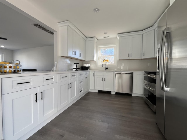 kitchen with dark hardwood / wood-style flooring, sink, white cabinets, and appliances with stainless steel finishes