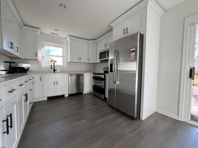 kitchen featuring appliances with stainless steel finishes, sink, white cabinets, and dark hardwood / wood-style flooring