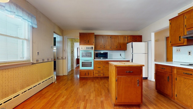 kitchen with double oven, a baseboard heating unit, a center island, white fridge, and light wood-type flooring