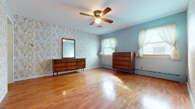 unfurnished bedroom featuring ceiling fan, light hardwood / wood-style flooring, and a baseboard heating unit