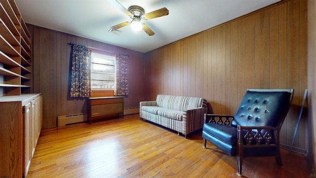 sitting room featuring ceiling fan, baseboard heating, and light hardwood / wood-style flooring