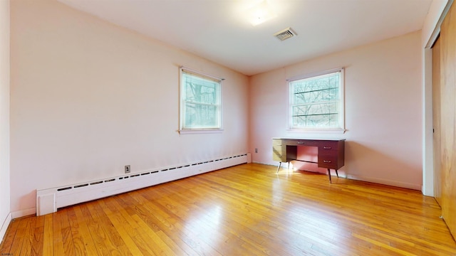 empty room with baseboard heating and light hardwood / wood-style flooring