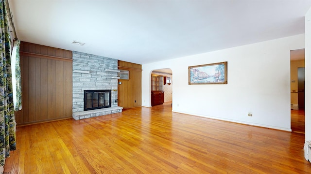 unfurnished living room with a stone fireplace and light hardwood / wood-style floors