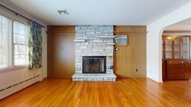 unfurnished living room with hardwood / wood-style flooring, a baseboard radiator, and a fireplace