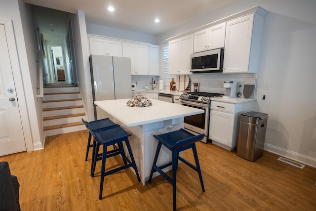 kitchen featuring sink, a breakfast bar area, stainless steel gas range oven, white cabinets, and a kitchen island