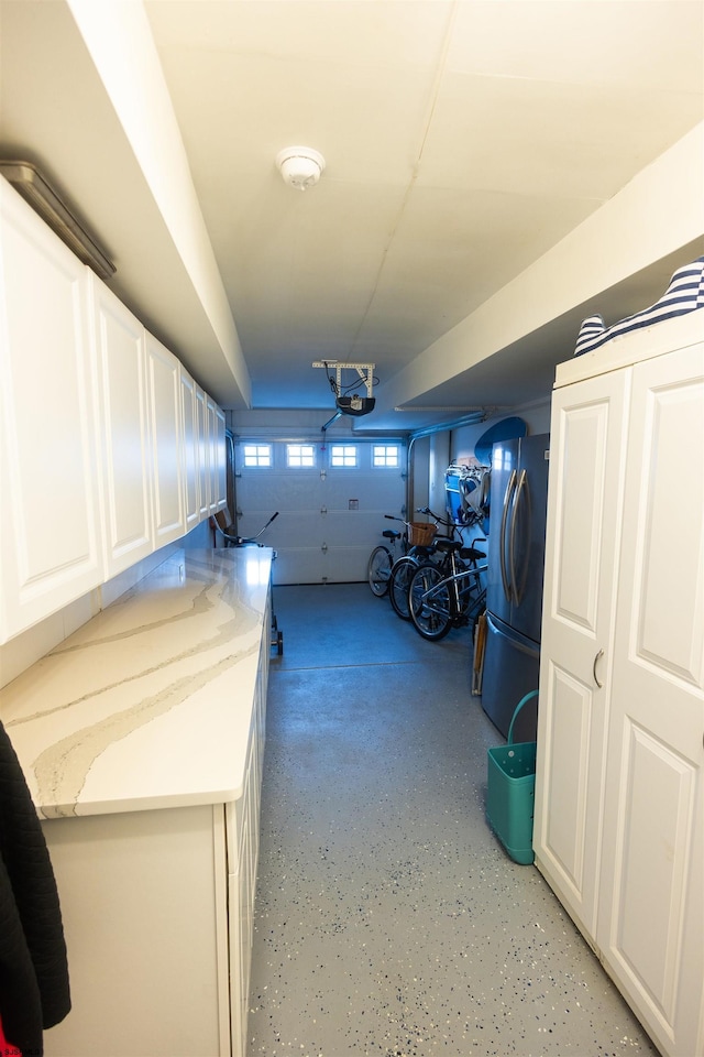 garage featuring stainless steel refrigerator and a garage door opener