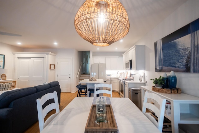 dining area with an inviting chandelier, sink, and light wood-type flooring