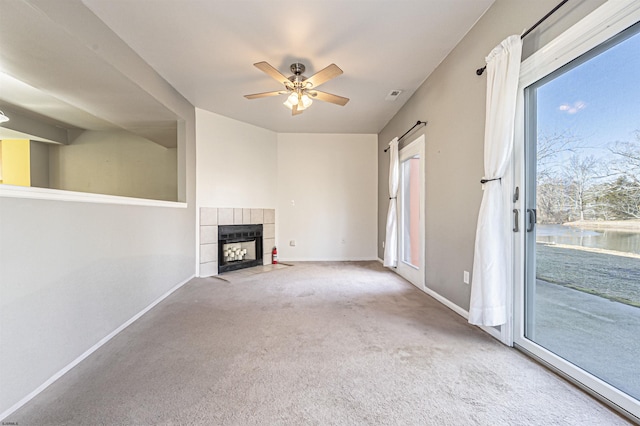 unfurnished living room featuring carpet flooring, a fireplace, ceiling fan, and a water view