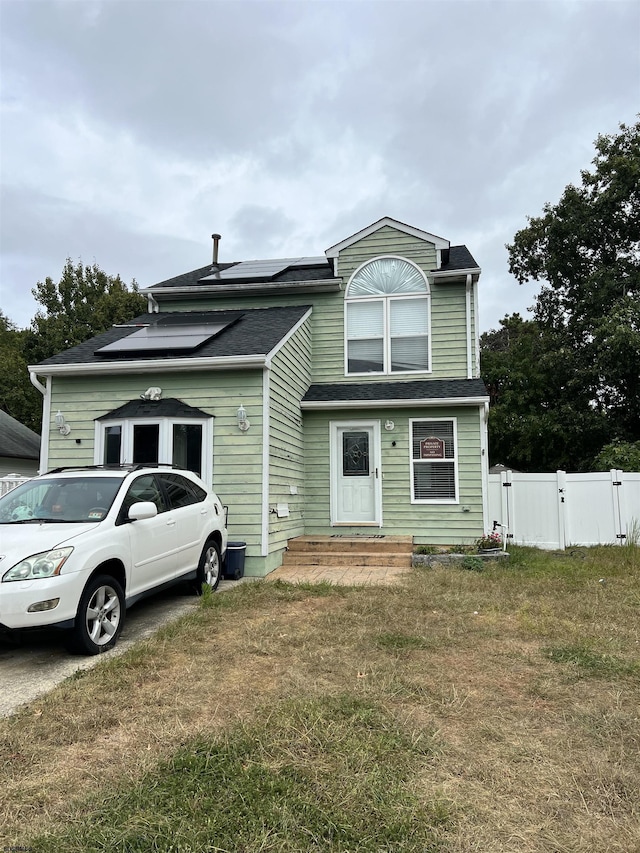 view of front of house with a front lawn and solar panels