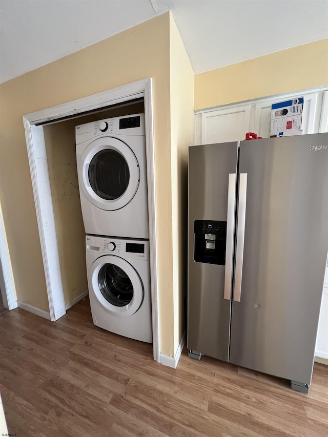 laundry area with stacked washer and dryer and light hardwood / wood-style floors