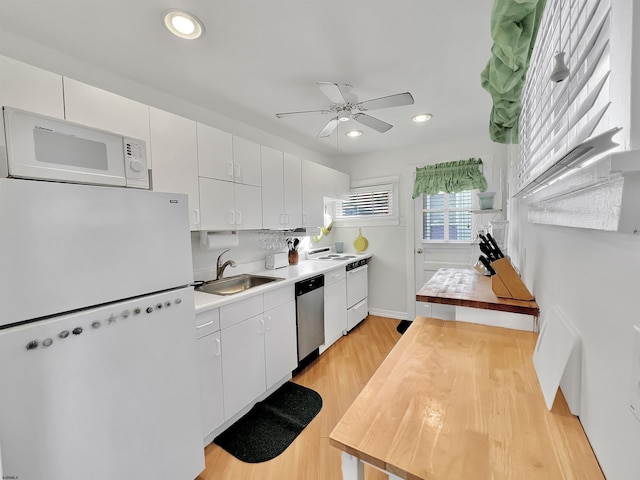 kitchen featuring sink, white appliances, light hardwood / wood-style flooring, and white cabinets