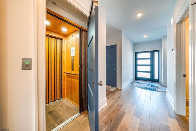 corridor featuring light hardwood / wood-style floors, a barn door, and elevator