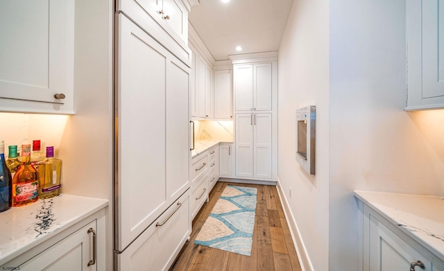 kitchen featuring white cabinetry, light hardwood / wood-style floors, and light stone counters