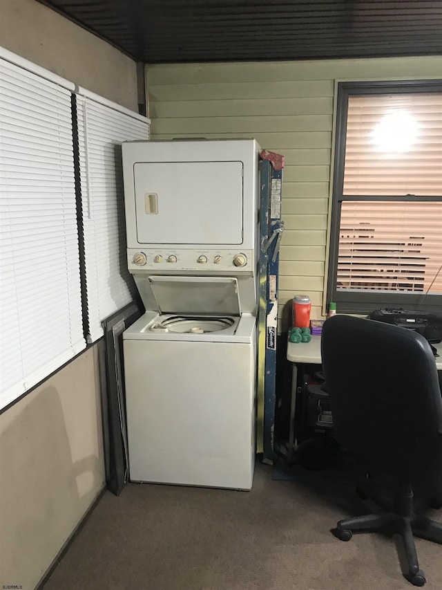 clothes washing area featuring carpet floors and stacked washer and clothes dryer