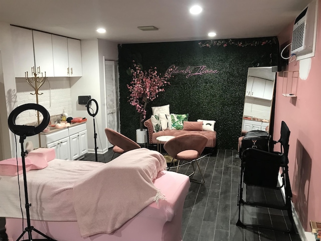 bedroom with a wall mounted AC and dark hardwood / wood-style flooring