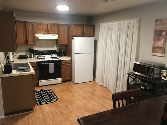 kitchen featuring sink, light hardwood / wood-style flooring, gas stove, and white fridge