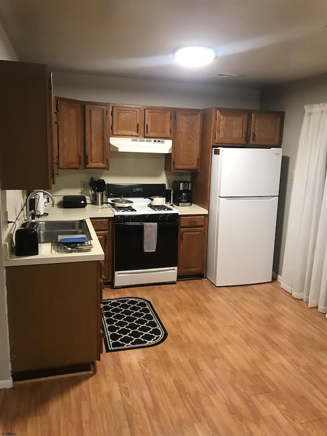 kitchen featuring white fridge, sink, range with gas cooktop, and light hardwood / wood-style flooring