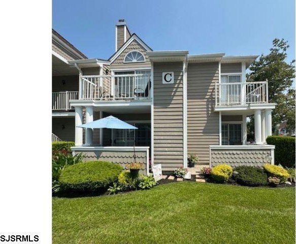 rear view of house featuring a balcony and a yard