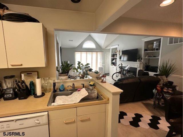 kitchen featuring white dishwasher, lofted ceiling, kitchen peninsula, and white cabinets