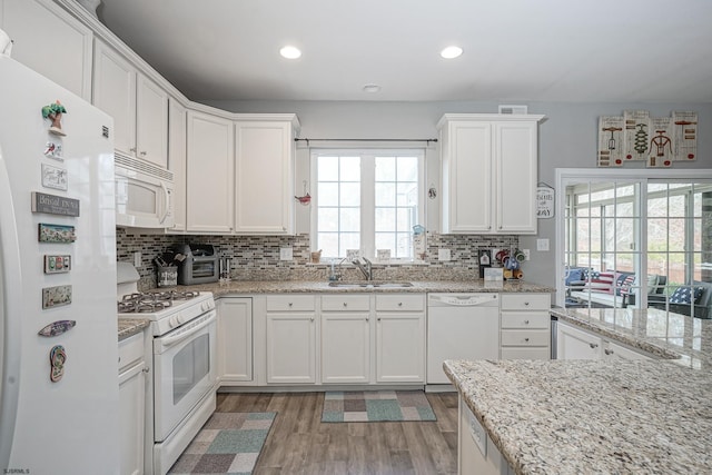 kitchen featuring tasteful backsplash, white cabinetry, sink, and white appliances