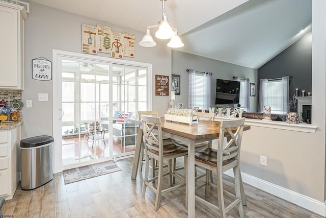 dining room featuring lofted ceiling and light hardwood / wood-style flooring