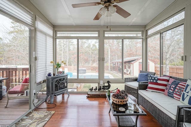 sunroom / solarium with ceiling fan and a wood stove