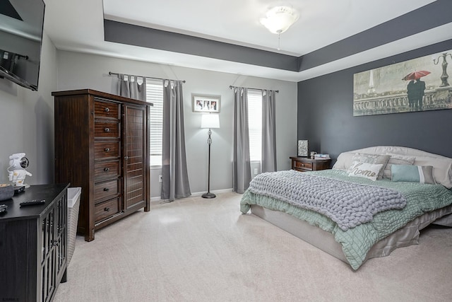 carpeted bedroom with a raised ceiling