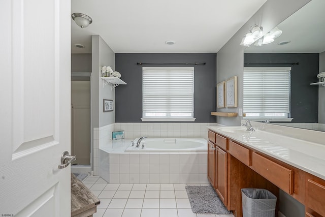 bathroom with a relaxing tiled tub, vanity, and tile patterned floors