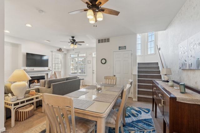 dining space with ceiling fan and a tile fireplace